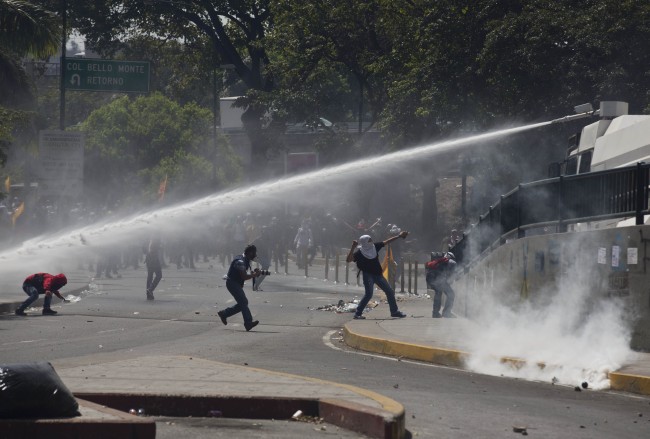 A water canon operated by Bolivarian National Police, sprays at protesters in Caracas, Venezuela, Thursday, March 20, 2014. Thursday dawned with two more opposition politicians, San Cristobal Mayor Daniel Ceballos and San Diego Mayor Enzo Scarano, behind bars. Police used tear gas and water cannons to disperse a student-called protest of several thousand people in Caracas, some of those demonstrating against the arrests of the mayors. 