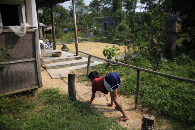In this photo taken on Oct. 5, 2009, Tran van Hoang walks on all fours as he returns to his family home in the village of Cam Tuyen, Vietnam. The young man was born with profound physical and mental disabilities that his family, and local officials, say were caused by his parents' exposure to the chemical dioxin in the defoliant Agent Orange.