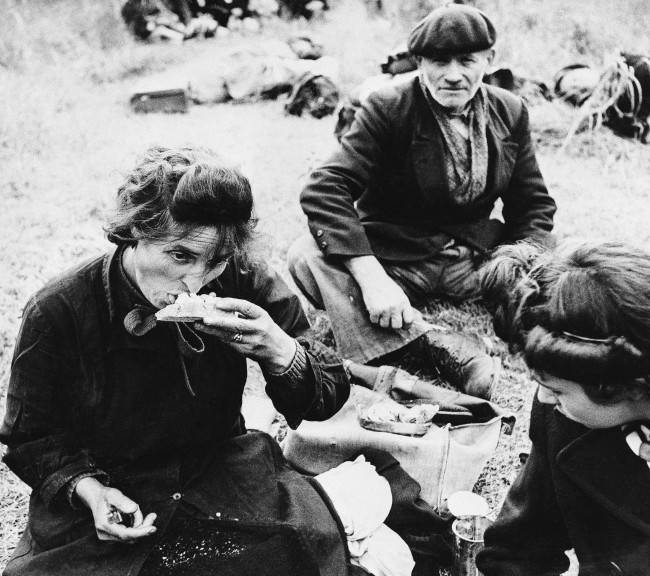 Many of these French refugees had not eaten for three or more days. In a field behind the allied lines they rest and receive food from our troops on June 20, 1944. The feeding arrangements were organized by the civil affairs dept. (AP Photo) 