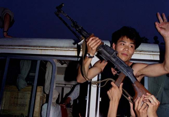 An anti-government protester in Beijing holds a rifle in a bus window, June 3, 1989. Pro-democracy protesters had been occupying Tiananmen Square for weeks; hundreds died that night and the following morning in clashes with Chinese troops. (AP Photo/Jeff Widener)